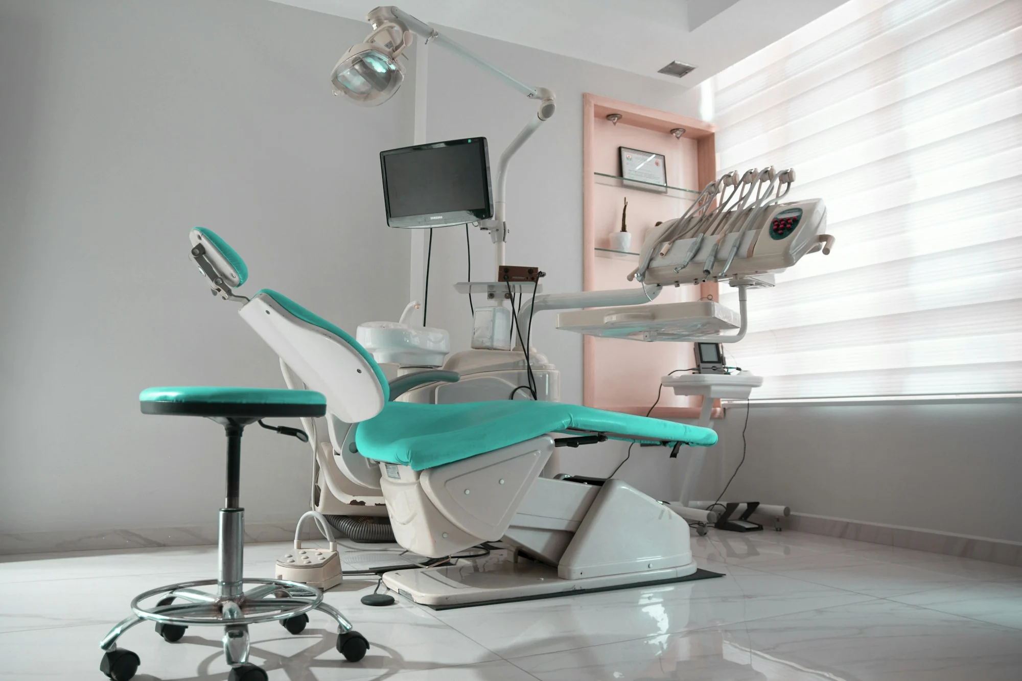 An unoccupied dental treatment room with a reclining chair and clinical equipment, illustrative stock photograph